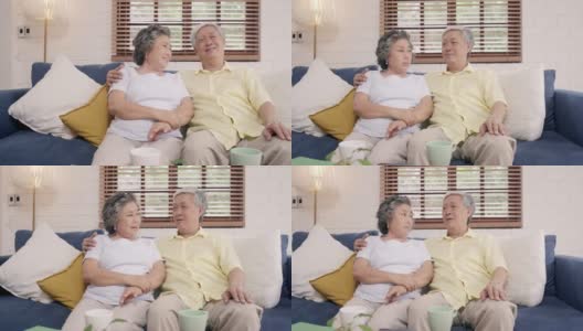 一对亚洲老夫妇在家里客厅的沙发上放松时，开心地微笑着，看着镜头。享受时光的生活方式高级家庭在家里的概念。看着相机的人像。高清在线视频素材下载
