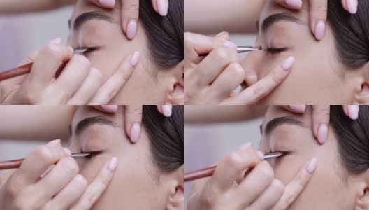 化妆师用画笔和眼影给亚洲女孩画眼线，特写高清在线视频素材下载