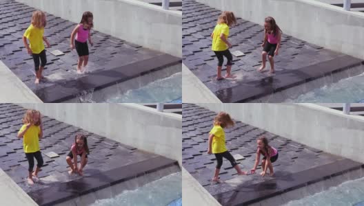 两个女孩在瀑布般的城市喷泉上戏水高清在线视频素材下载