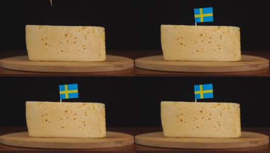 男人的手把小牙签放在奶酪上，上面有瑞典国旗。高清在线视频素材下载