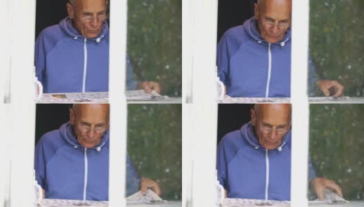 一名退休男子在窗外玩填字游戏高清在线视频素材下载
