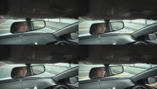 一位亚裔中国妇女坐在驾驶座上，在城市道路上开车高清在线视频素材下载