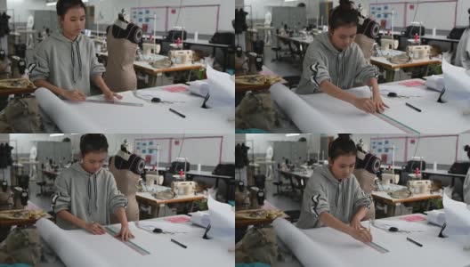 亚洲华裔女时装大学生在学院车间做服装项目，写下尺寸，画出缝纫图案高清在线视频素材下载