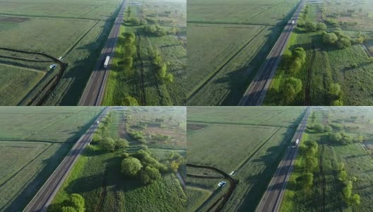 一辆卡车在太阳升起的绿色田野之间的道路上行驶的全高清航拍镜头高清在线视频素材下载