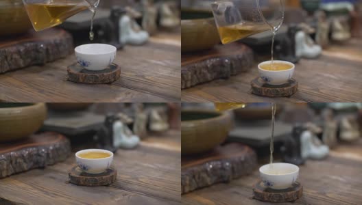 用慢动作将泡好的绿茶从玻璃茶壶中倒入白色陶瓷杯中高清在线视频素材下载