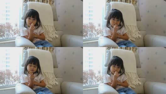一个亚洲小女孩在家里吃零食高清在线视频素材下载