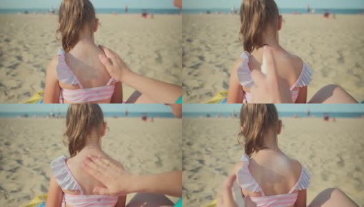 在家庭度假的海滩上，一位年轻的母亲在她五岁女儿的背上涂抹防晒霜或防晒霜来保护她的皮肤。高清在线视频素材下载