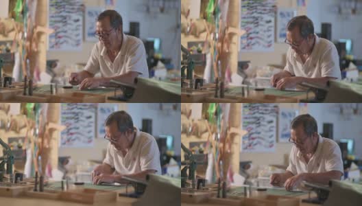 一位亚洲华人老人在他的工作室里制作手工皮革表带高清在线视频素材下载