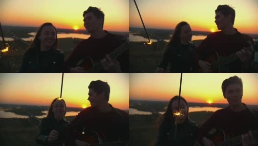 年轻幸福的夫妇一起玩火花唱歌与吉他在户外日落高清在线视频素材下载