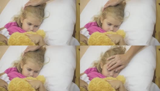 生病的小女孩在发烧。小孩发烧:女人抚摸小孩的头。特写镜头。高清在线视频素材下载