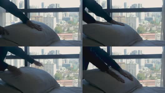 一个人正在为一张新铺的床整理枕头，俯瞰着一个城市高清在线视频素材下载