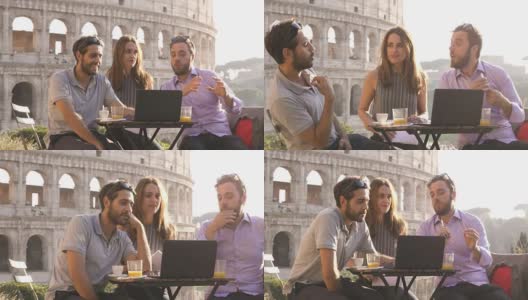 夕阳西下时，三个年轻人坐在罗马圆形大剧场前的酒吧餐厅餐桌前，用笔记本电脑在外面一起工作，进行视频通话高清在线视频素材下载