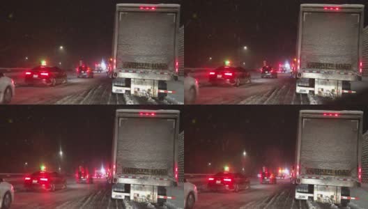 在暴风雪的夜晚，在州际公路上被事故和紧急救援人员拦下时，从一辆车的前面拍摄的高清在线视频素材下载