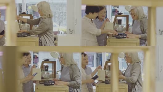 两名亚洲妇女在商店用手机付款的慢动作视频高清在线视频素材下载