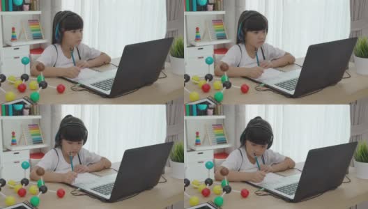 亚洲女学生视频会议电子学习科学课与老师和同学在家里的客厅电脑上。在家教育和远程学习，在线，教育和互联网。高清在线视频素材下载