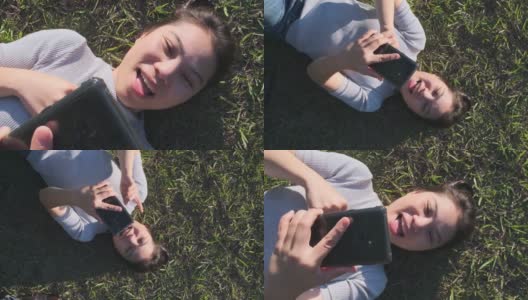 幸福开朗的亚洲女性成熟的成年人手持智能手机交流放松随意躺在绿色草地上与阳光在花园公园的背景高清在线视频素材下载