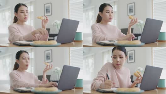 年轻迷人美丽的亚洲女性饿了吃甜甜圈，吃零食吃满嘴看电脑笔记本在家里在忙碌的工作，从家里多任务不健康的饮食生活理念。高清在线视频素材下载