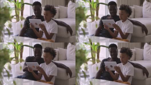 十几岁的非洲男孩在平板电脑Spbi上播放爸爸的电影。一家人一起看视频。享受高清在线视频素材下载