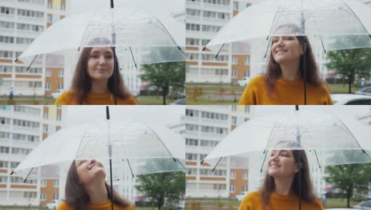 快乐的年轻女子站在雨中透明的伞下高清在线视频素材下载