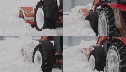 冬天，一辆带着黄色铲斗的拖拉机在街上铲雪。道路清扫援助。慢动作高清在线视频素材下载