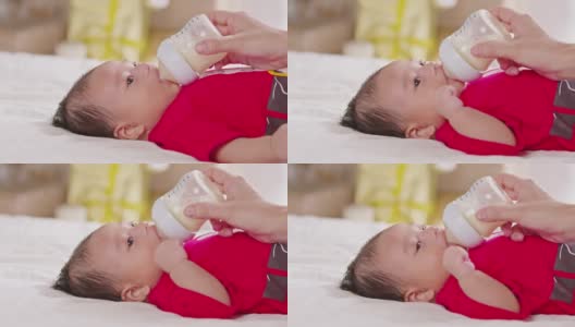 新生儿躺在床上喝着牛奶。可爱的婴儿宝宝用爱在家里喂奶。新生的概念高清在线视频素材下载
