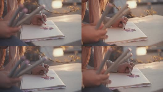女孩正在户外公园里画画，用记号笔和图片的手的特写高清在线视频素材下载