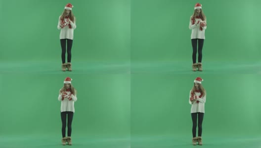 迷人的年轻女子在圣诞帽看她的圣诞礼物，色度键的背景高清在线视频素材下载