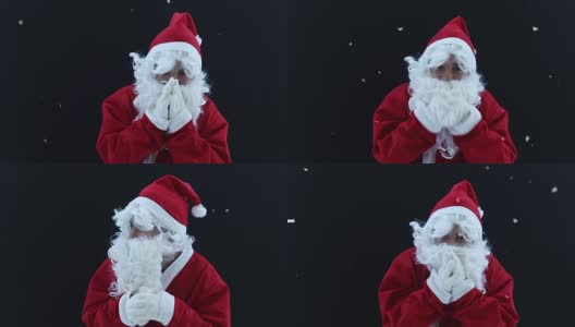 圣诞老人瑟瑟发抖，双手放在黑色背景前取暖高清在线视频素材下载