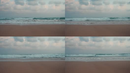 美丽的暴风雨在阴天。海浪翻滚到日落的海滩上。高清在线视频素材下载