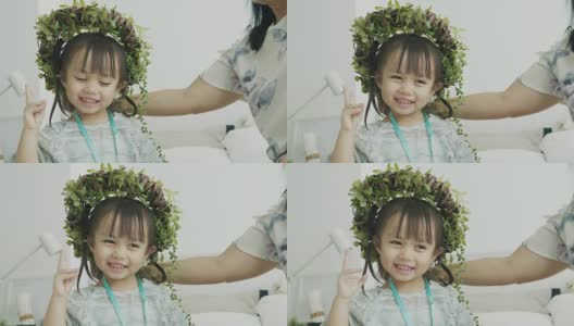 泰国可爱的小女孩戴着花叶冠微笑着，情绪愉快高清在线视频素材下载