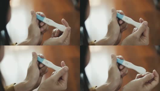 一名亚洲孕妇抱着阳性孕检在卧室里高清在线视频素材下载