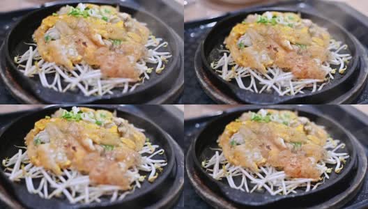 特写慢镜头的泰国食物或街头食物在热盘在餐厅服务。用面粉和豆芽炒生蠔，盛于热板内。高清在线视频素材下载