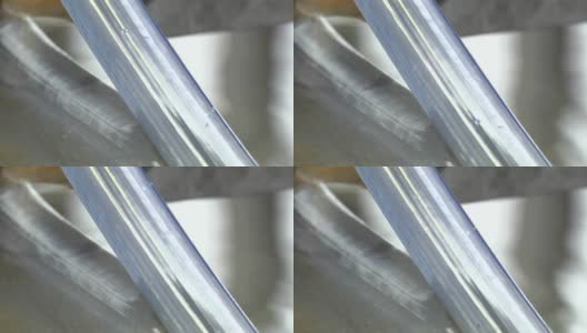 在工厂生产透明硅胶管。在机床上用水制造塑料管的过程。用热水冷却软管。软管被拉过滚筒。高清在线视频素材下载