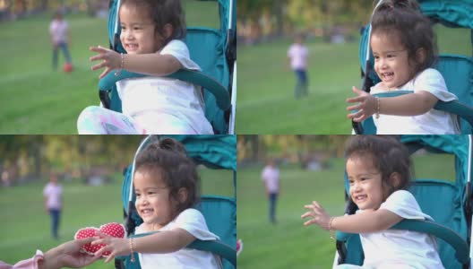 亚洲穆斯林家庭在公园里，母亲和女儿在花园里玩，女孩坐在婴儿车上高清在线视频素材下载
