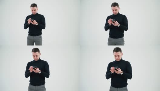 有创意的商人正在研究智能手机。英俊的男子在黑色毛衣使用手机孤立在白色演播室背景。高清在线视频素材下载
