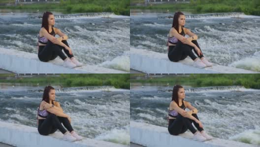 一位梳着许多辫子的年轻女子穿着运动服，坐在湍急的河流中。高清在线视频素材下载