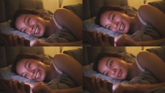 一个亚洲女人在床上玩手机高清在线视频素材下载