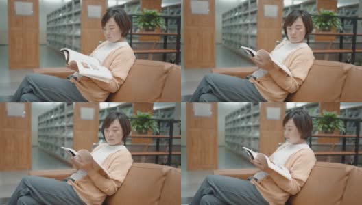 亚洲女人在图书馆的书架上看书高清在线视频素材下载