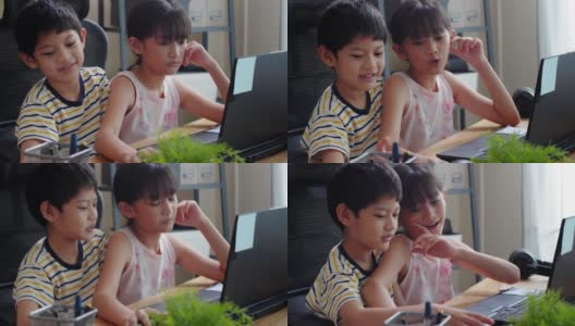 亚洲兄妹在家里用笔记本电脑玩网络游戏的时候聊天。维系和分享爱的家庭高清在线视频素材下载