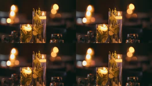 婚礼宴会厅的内部细节与装饰餐桌设置在餐厅。蜡烛和白色花瓣装饰玫瑰花在玻璃花瓶装满水高清在线视频素材下载