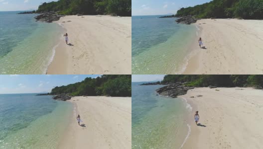 一个穿着白色裙子的女孩正沿着海边跑步。高清在线视频素材下载