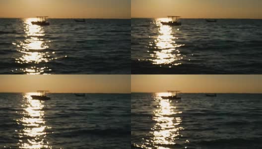 4K镜头抽象模糊背景。日落或日出时海面上小船的剪影，夏日热带海滩上美丽的阳光反射在水面上高清在线视频素材下载