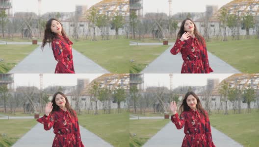 一个穿着红色裙子的美丽中国女孩转身挥手告别她的朋友的肖像，4k视频，慢镜头。高清在线视频素材下载