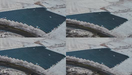 在雪地里使用太阳能可再生电池板生产的太阳能农场在冬天没有汽车或卡车的空旷道路附近供电高清在线视频素材下载