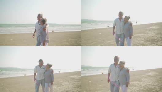 亚洲老夫妇手牵着手一起走在沙滩上，在夏天的日落。高清在线视频素材下载