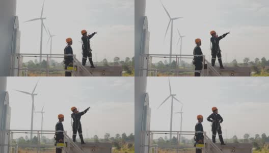 在泰国风电场，两名亚洲工程师在统一的检查工程师准备和进度检查风力发电机的安全。高清在线视频素材下载