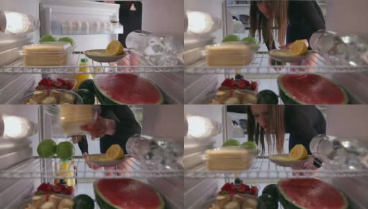 年轻女子从冰箱里拿出橙汁、奶酪、鳄梨高清在线视频素材下载