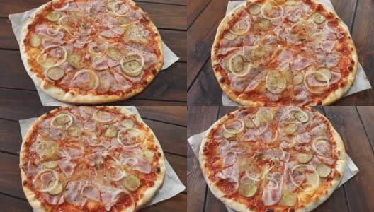 新鲜的圆形披萨，配上马苏里拉奶酪、意大利腊肠、黄瓜和洋葱，在棕色木桌上旋转。披萨店的美味快餐背景高清在线视频素材下载