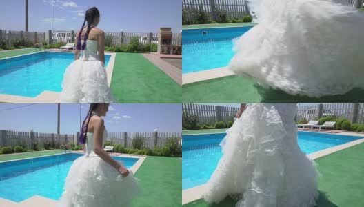 穿着白色婚纱的年轻女孩沿着室外游泳池散步高清在线视频素材下载