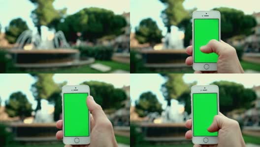 在喷泉背景下的公园里使用手机应用高清在线视频素材下载